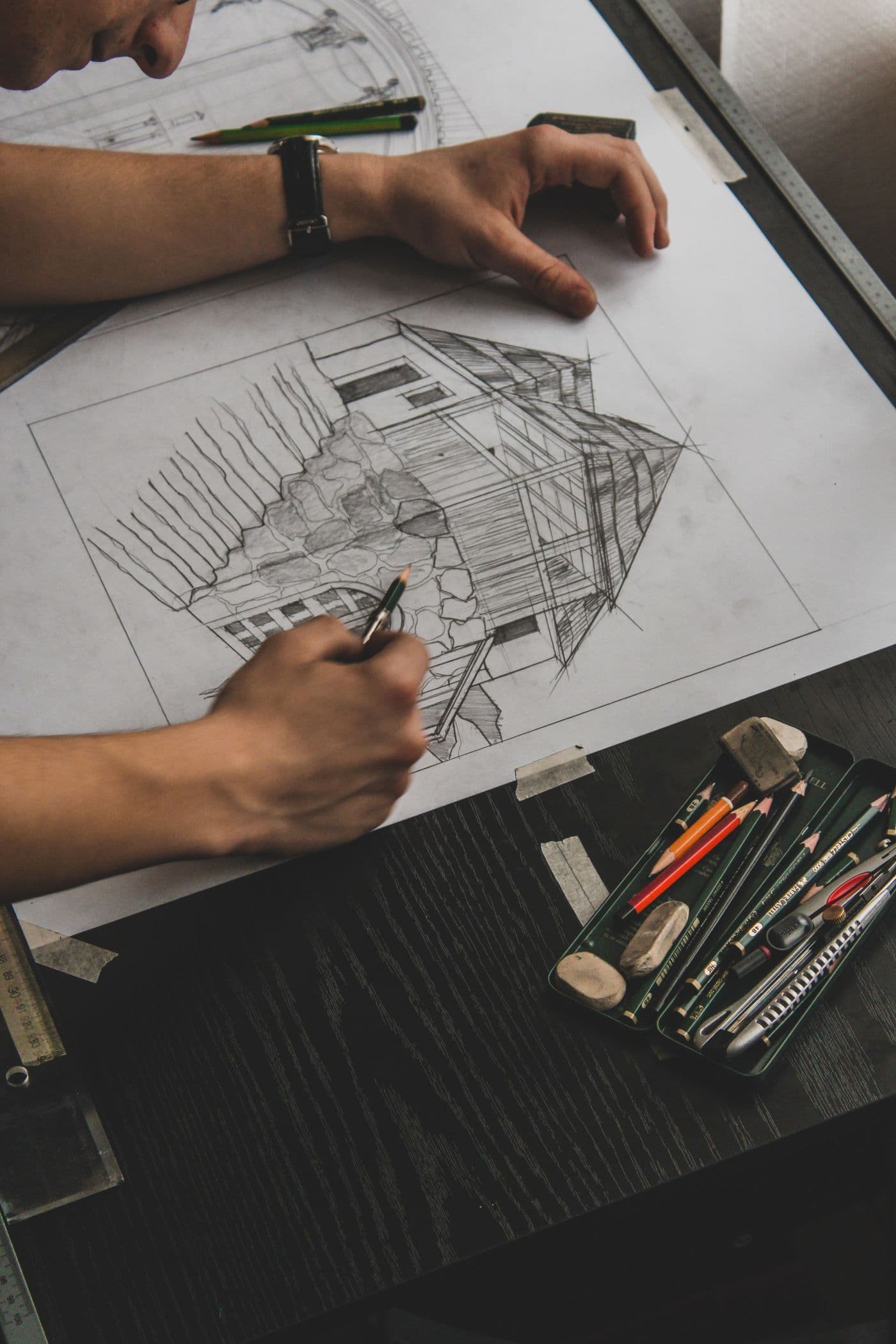 An architect drawing a home by hand in pencil and ink